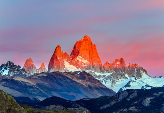 The grand crimson dawn over the mountain Fitzroy. Mountain peak in Patagonia. Magnificent mountain range, illuminated by the sunrise sun. The concept of extreme, active and photo tourism